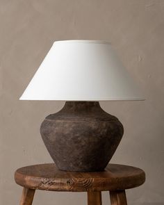 a table lamp sitting on top of a wooden stool next to a white lampshade