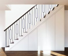 an empty room with white walls and wooden flooring next to a set of stairs