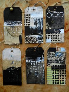 four tags with black and white designs are hanging on a piece of paper that has string attached to it