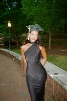 a woman wearing a graduation cap and gown posing for a photo in front of a brick wall