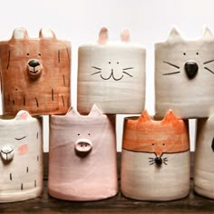 a group of ceramic cats sitting on top of a wooden shelf next to each other