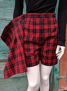 This little skort has a classic look that can carry you from the tennis court to the hunt club and anywhere in between! Poly-blend fabric in red/back tartan plaid, simple banded waist with side button attachment for front panel, front zipper, front side pleats on shorts, unlined, very nice condition with one note: It appears the skirt portion may have been pinned as there are a couple of pin holes (see pictures) on the side. Size 4, 1980s. The following measurements were taken with the garment l Plaid Cotton Skort For Fall, Red Cotton Shorts For School, Plaid Cotton School Bottoms, Retro Pleated Short Skort, Retro Plaid School Bottoms, Red Pleated Short Skort, Plaid School Uniform Skort, Red Pleated Mini Skort, Pleated Plaid Cotton Skort