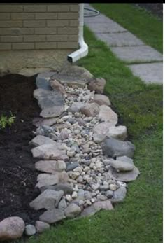 a pile of rocks sitting on top of a grass covered ground next to a house