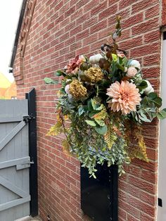 a bunch of flowers hanging from the side of a brick wall next to a door