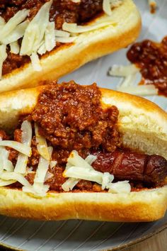 two hot dogs with chili and cheese on a plate