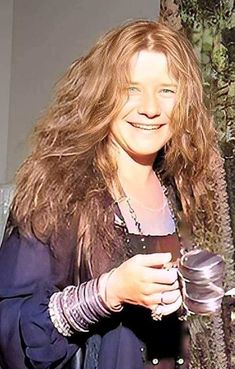 a woman standing next to a tree holding a cup