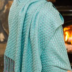 a woman wearing a blue shawl standing in front of an oven