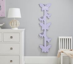 a room with a white dresser and purple butterflies on the wall