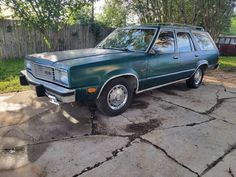 a green station wagon is parked in the driveway