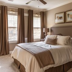 a bed sitting in a bedroom next to two windows with drapes on each side