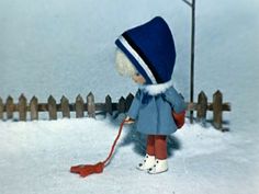 a little boy that is standing in the snow with a hockey stick and wearing a hat