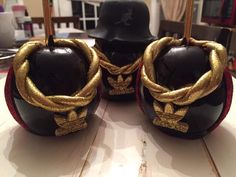 two black and gold decorated apples sitting on top of a white table next to a hat