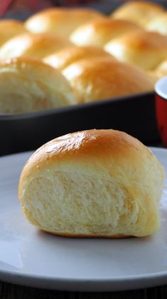 a close up of a piece of bread on a plate near a tray of rolls