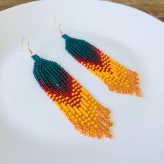 a pair of beaded earrings sitting on top of a white plate