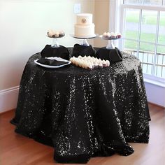 the table is covered with black sequins and white frosted cake on it