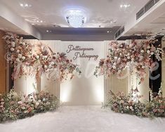 an indoor wedding ceremony setup with flowers on the wall and chandeliers hanging from the ceiling