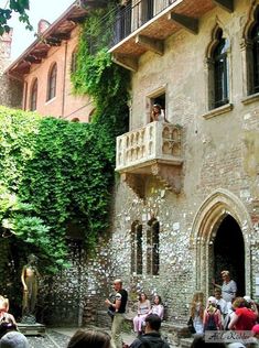 a group of people standing in front of a building with ivy growing on the walls