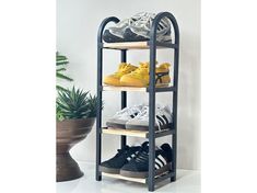 three tiered shoe rack with various pairs of shoes on top and bottom shelves, in front of a potted plant