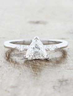 a white gold and diamond ring sitting on top of a wooden table