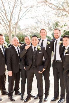 a group of men standing next to each other wearing black suits and white shirts on their wedding day