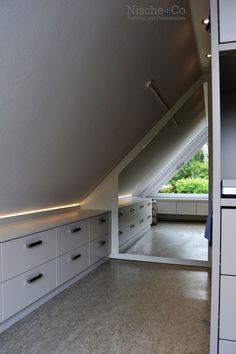 an attic bedroom with white cabinets and drawers