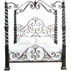 an iron bed frame with white sheets and pillows