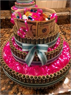 a three tiered cake decorated with dollar bills and pink ribbon, on top of a granite countertop