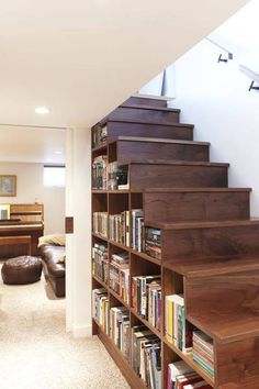 there is a bookshelf with many books on it next to the stairs in this room