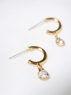 "Modern huggie hoop earrings with a sparkly cubic zirconia gem for a little sway and shimmer. Dangling from secure sterling silver stud hoops for secure and easy wear. MATERIALS [ SILVER ] sterling silver hoop, rhodium silver filled charm, AAAAA cubic zirconia [ GOLD ] 14k gold vermeil hoop, 14k gold filled charm, AAAAA cubic zirconia DIMENSIONS ◊ hoops measure 11mm (7/16\") in diameter and about 1.5mm (1/16\") thick ◊ 21mm (13/16\") length with drop ◊ 4mm (5/32\") gem ◊ More cz jewelry: https:/ Dainty Hoop Jewelry With Prong Setting, Small Hoop Cubic Zirconia Crystal Earrings, Dainty Huggie Jewelry With Prong Setting, Dainty Hoop Jewelry With Dangling Charms, Minimalist Dangle Hoop Earrings With Prong Setting, Minimalist Hoop Earrings With Prong Setting, Minimalist Dangle Hoop Earrings Cubic Zirconia, Delicate Huggie Jewelry With Cubic Zirconia, Delicate Cubic Zirconia Huggie Jewelry