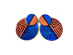 two blue and orange circular earrings with geometric designs on the front, one has an orange circle