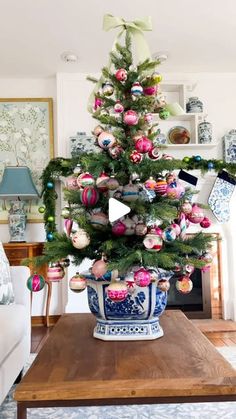 a decorated christmas tree in a blue and white bowl on a coffee table next to a fireplace