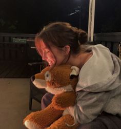 a woman is holding a stuffed animal in her arms and laughing at the camera with an open mouth