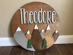 a wooden sign that says theodore with mountains and trees