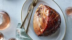 a piece of meat sitting on top of a white plate next to wine glasses and utensils