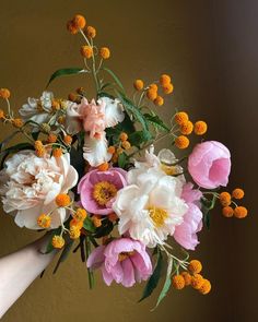 a person holding a bouquet of flowers with orange and white blooms in it's hand