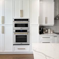 a kitchen with marble counter tops and white cabinets, including an oven that is built into the wall