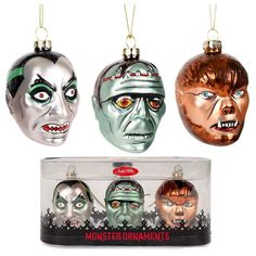 three christmas ornaments in the shape of zombies and other creepy faces are hanging from chains