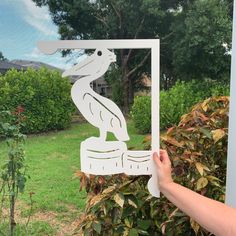 a person is holding up a cutout of a bird on a post in front of some bushes