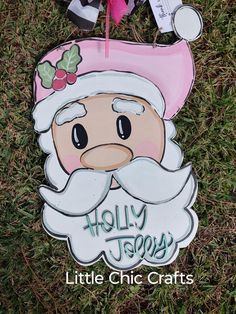 a sign that says holly jolly and has a santa clause on it, sitting in the grass