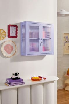 a white table topped with plates and bowls next to a wall mounted cabinet on the wall