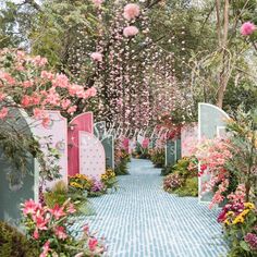 a garden filled with lots of pink flowers and green gates surrounded by lush greenery