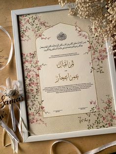 an arabic wedding card with flowers and ribbons on a wooden table next to some ribbon