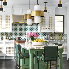 a kitchen with white cabinets and green accents on the countertop, along with an island in the middle