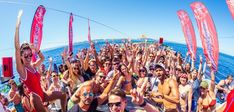 a group of people standing on top of a boat in the ocean holding up their hands