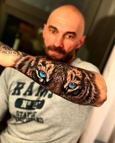 a man with a tattoo on his arm has blue eyes and a tiger design on it