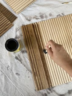 a person is painting wood planks on the floor with black paint and a cup of coffee