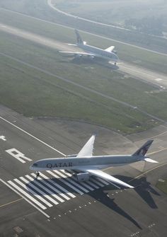 two airplanes are flying over an airport runway