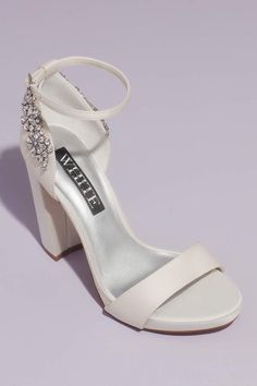 a pair of white high heeled shoes with jewel embellishment on the ankle