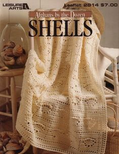 an afghan is sitting on a chair next to shells and a basket full of seashells