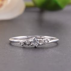 a three stone diamond ring sitting on top of a table next to a white flower